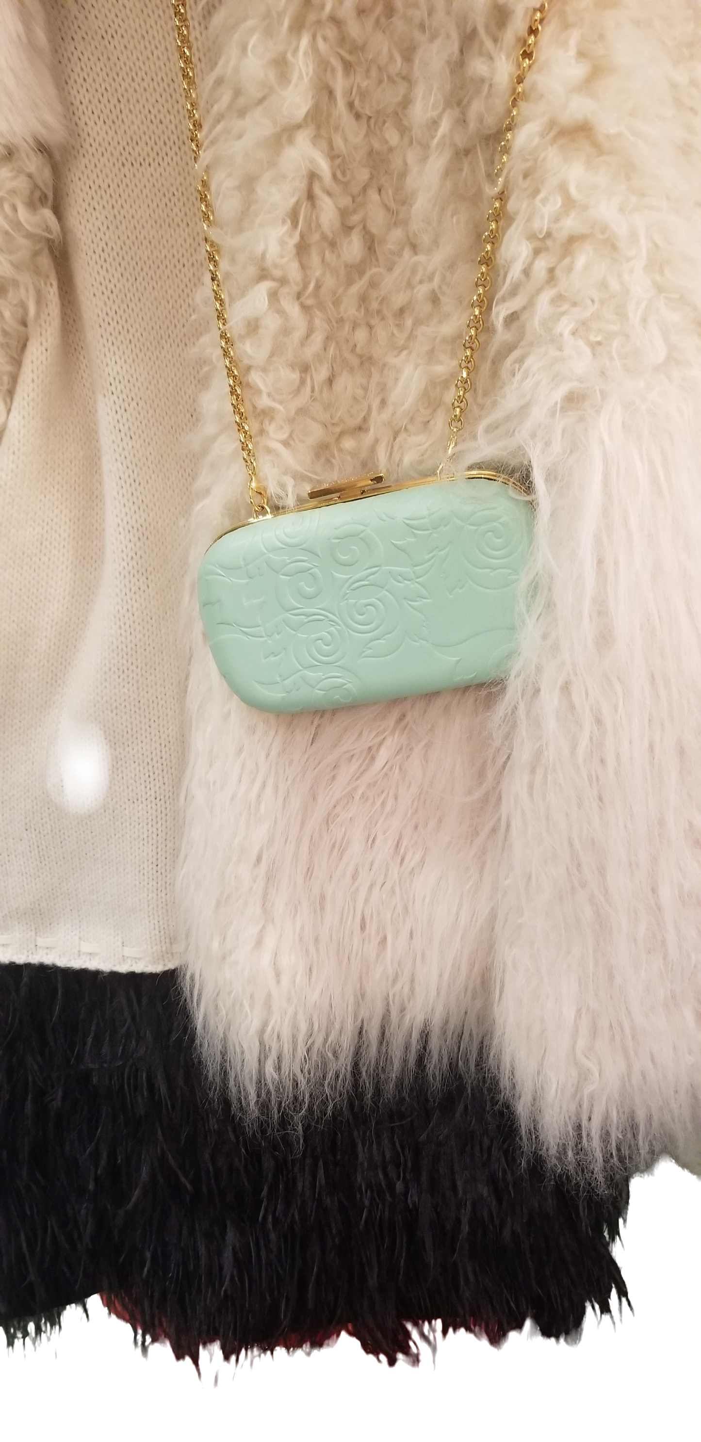 Stylish light green Versace clutch with gold chain, resting against a textured wool sweater.