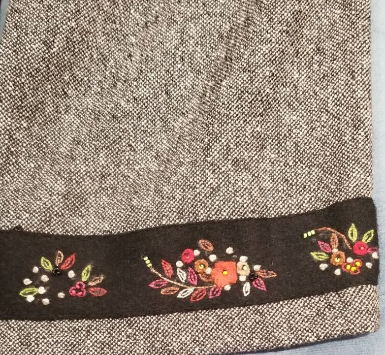 Close-up of Marccain gray straight pants featuring elegant flower embroidery detail at the hem.