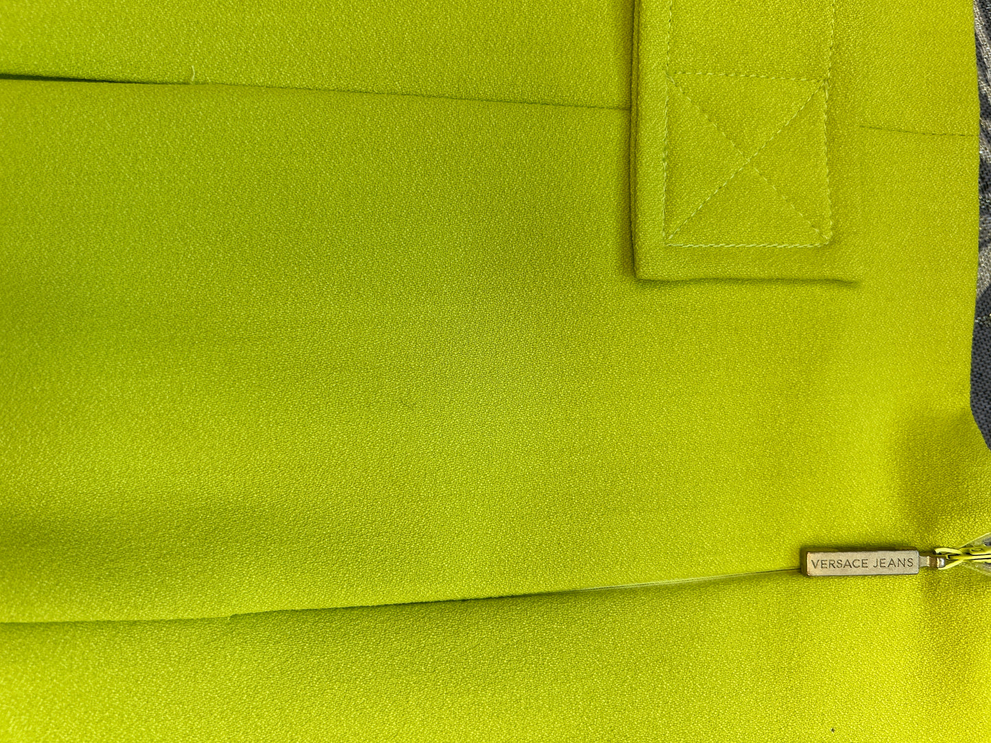 Close-up of Versace fluorescent green skirt showcasing fabric texture and branding detail.