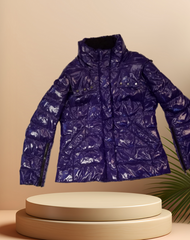 Marccain Royal Blue Reversible Quilted Jacket displayed on a pedestal, showcasing its futuristic design and shiny finish.