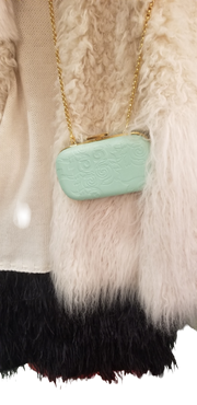 Stylish light green Versace clutch with gold chain, resting against a textured wool sweater.