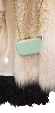 Stylish light green Versace clutch with gold chain, resting against a textured wool sweater.