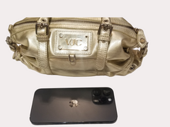 Stylish gold handbag with logo detail next to a smartphone, perfect for trendy outings.