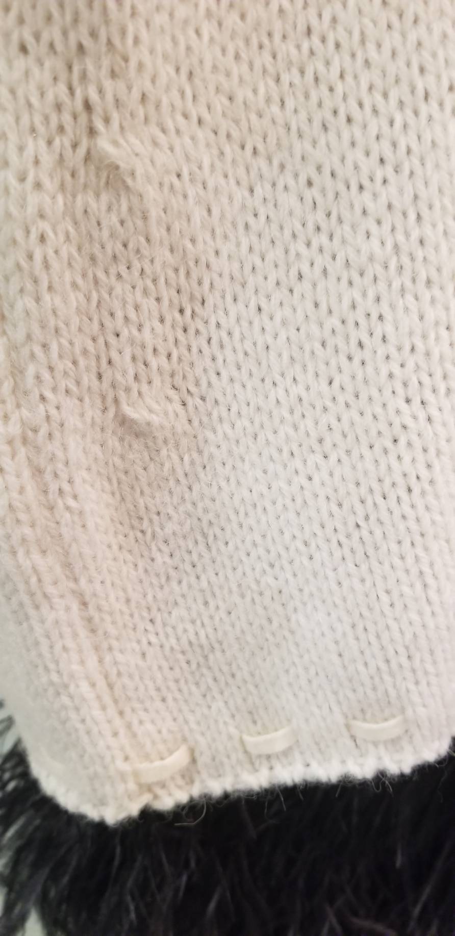 Close-up of the creamy white fabric texture of the Laurel Sweater, showcasing its fine knit and detailing.