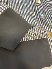 Close-up of Versace black and white checked jacket fabric and cuff detail, showcasing elegant design elements.