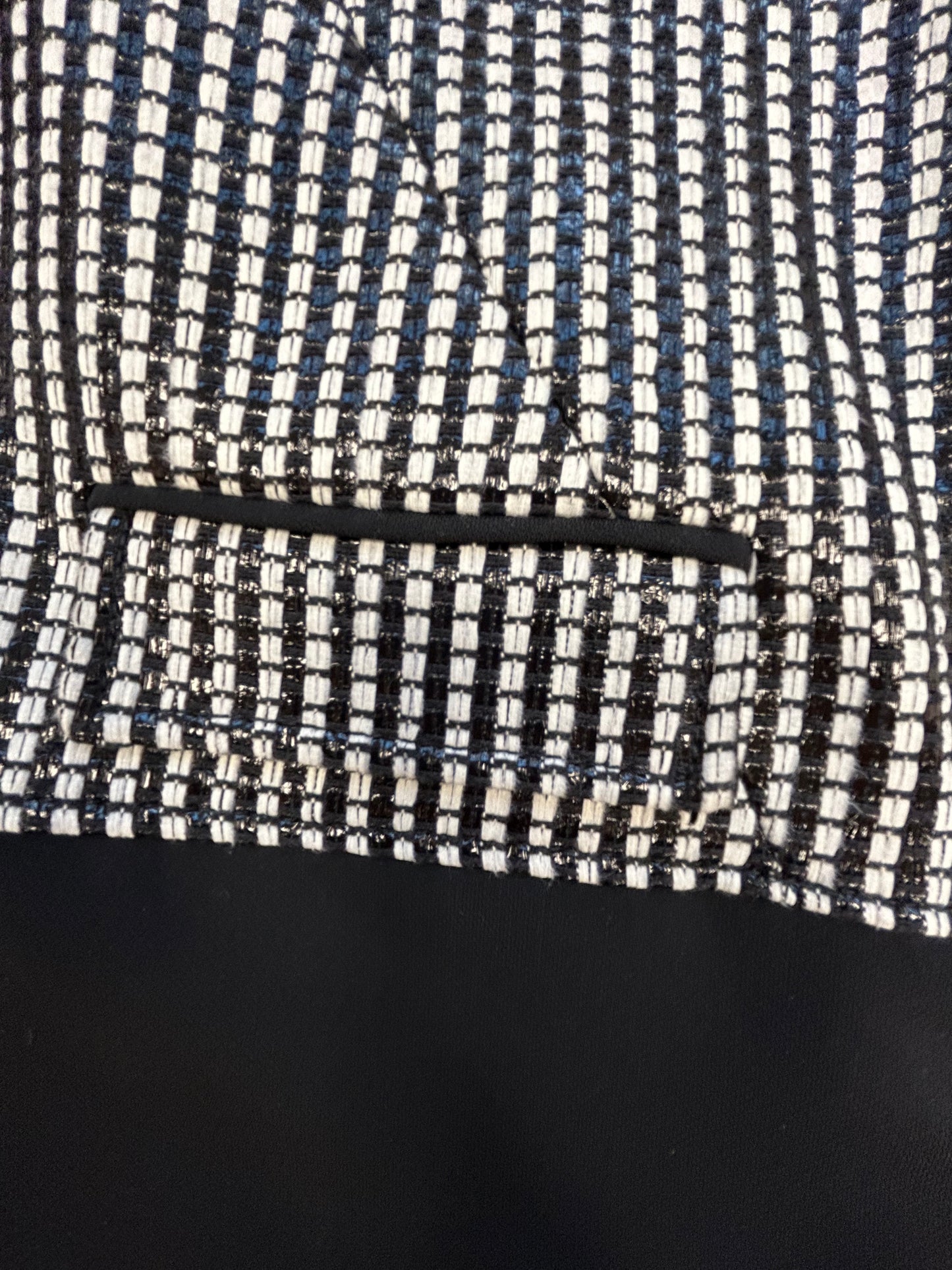 Versace black and white checked jacket detail, showcasing intricate fabric pattern and stylish pocket design.