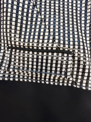 Versace black and white checked jacket detail, showcasing intricate fabric pattern and stylish pocket design.