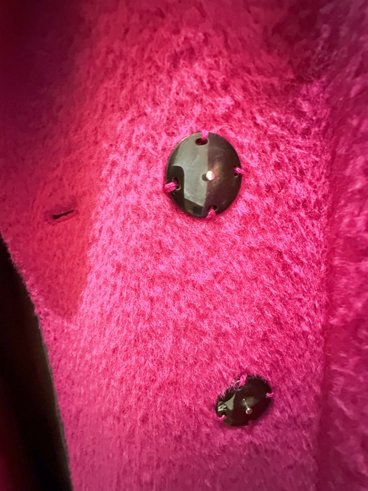 Close-up of buttons on a luxurious Marccain hot pink coat, showcasing its vibrant color and soft texture.