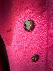 Close-up of buttons on a luxurious Marccain hot pink coat, showcasing its vibrant color and soft texture.
