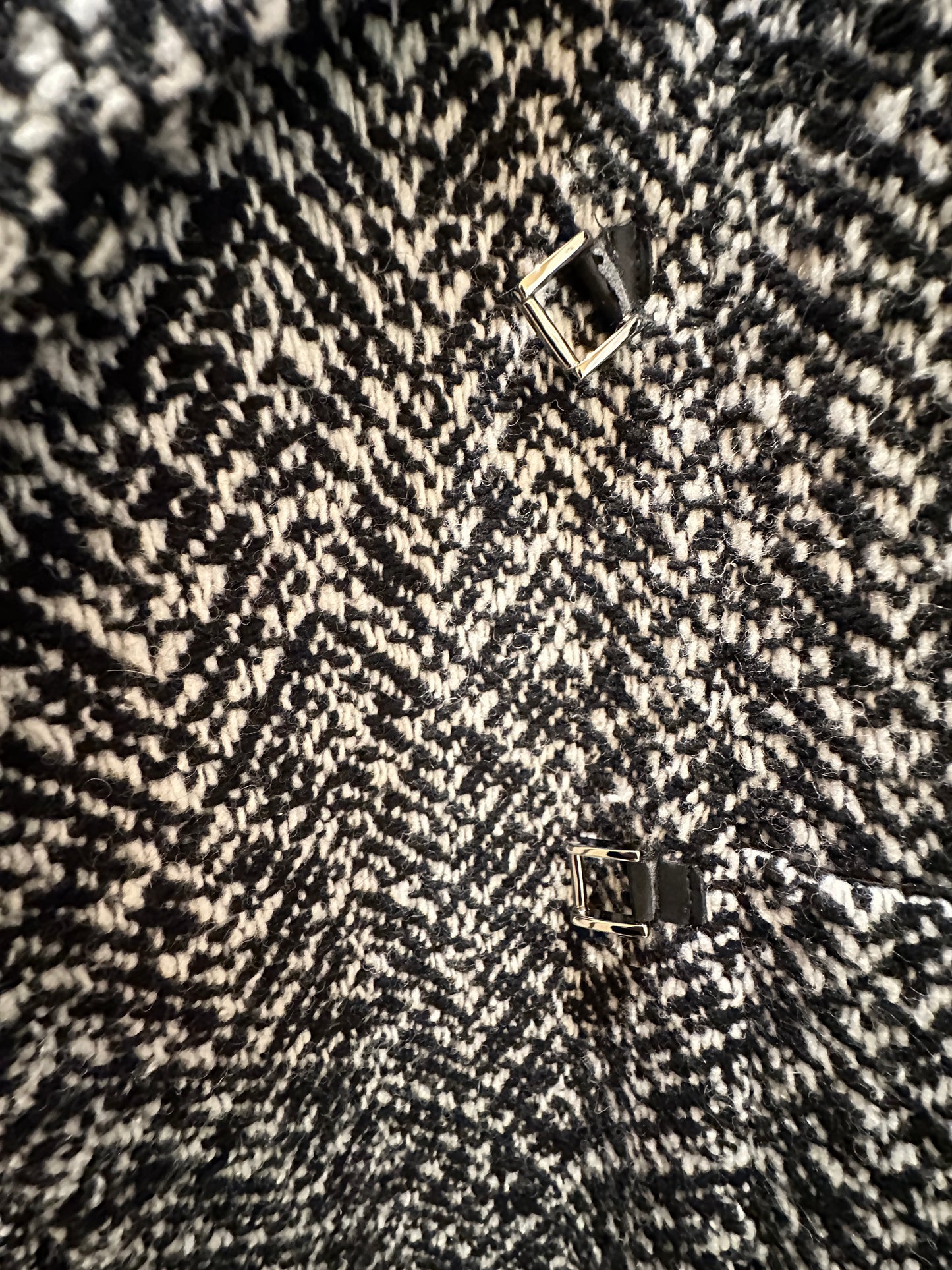 Close-up of Marccain black and white houndstooth coat fabric with leather accents and distinctive pattern.