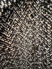 Close-up of Marccain black and white houndstooth coat fabric with leather accents and distinctive pattern.