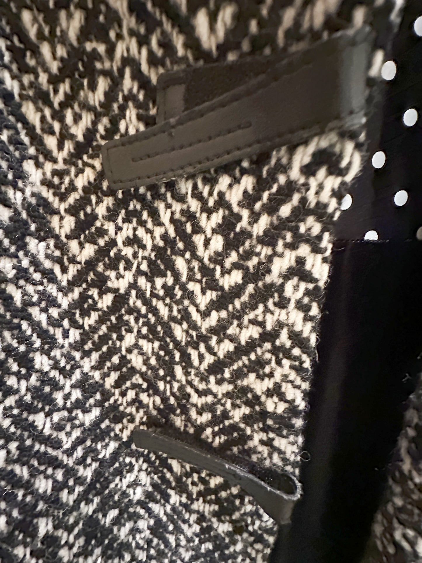 Close-up of Marccain black and white houndstooth coat featuring leather accents, perfect for modern fashion.