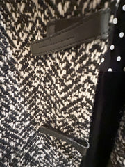 Close-up of Marccain black and white houndstooth coat featuring leather accents, perfect for modern fashion.