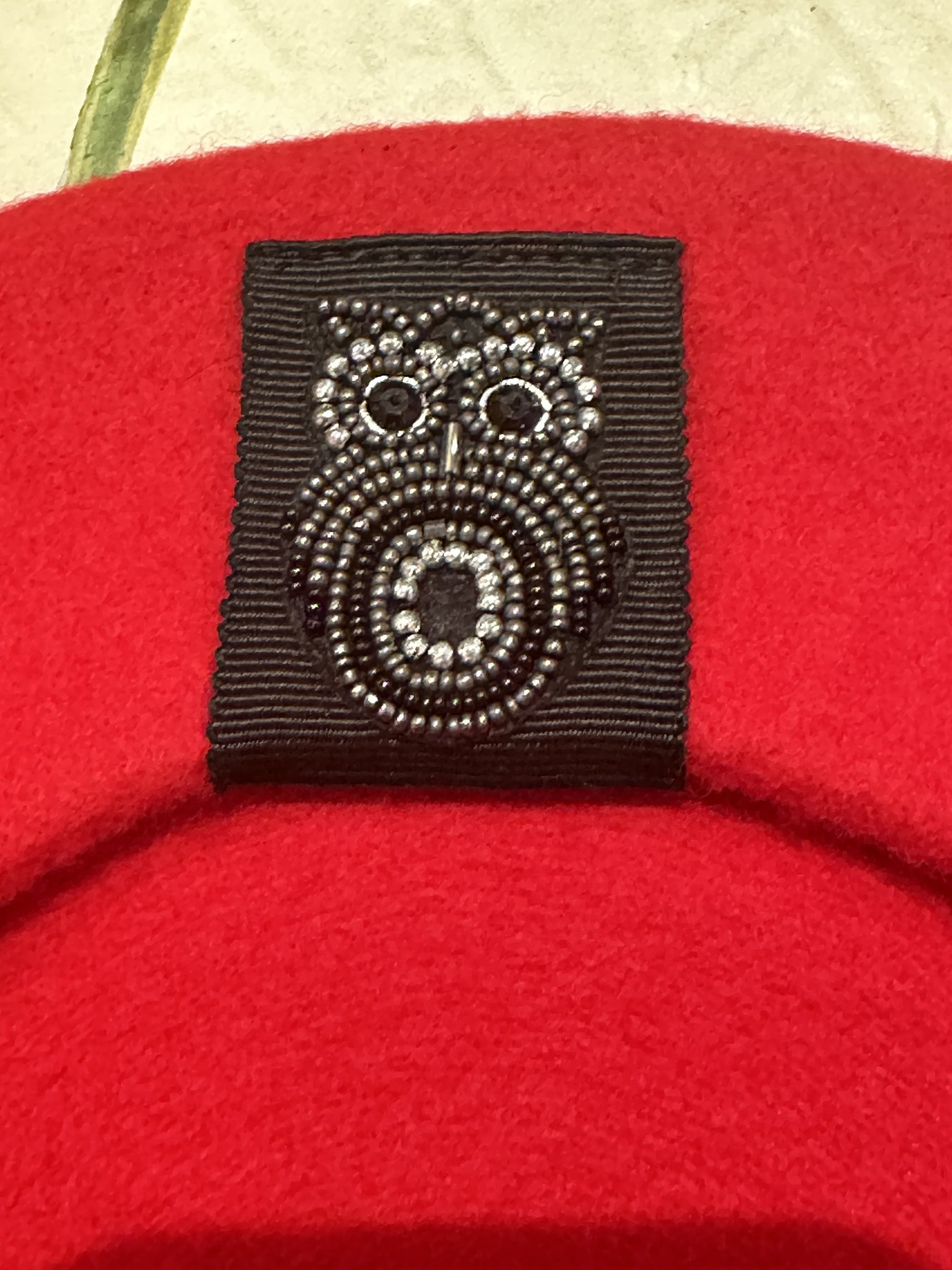 Close-up of intricate insect beading decoration on a red wool beret from Seventy Berets.