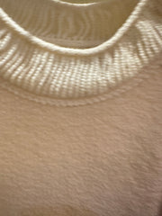 Close-up of Marccain sweater's luxurious fabric and ribbed neckline in creamy color.