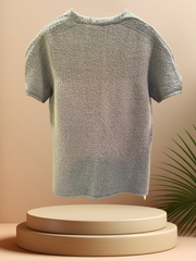 Back view of a light blue Marccain blouse, showcasing its textured fabric and stylish design, perfect for winter fashion.