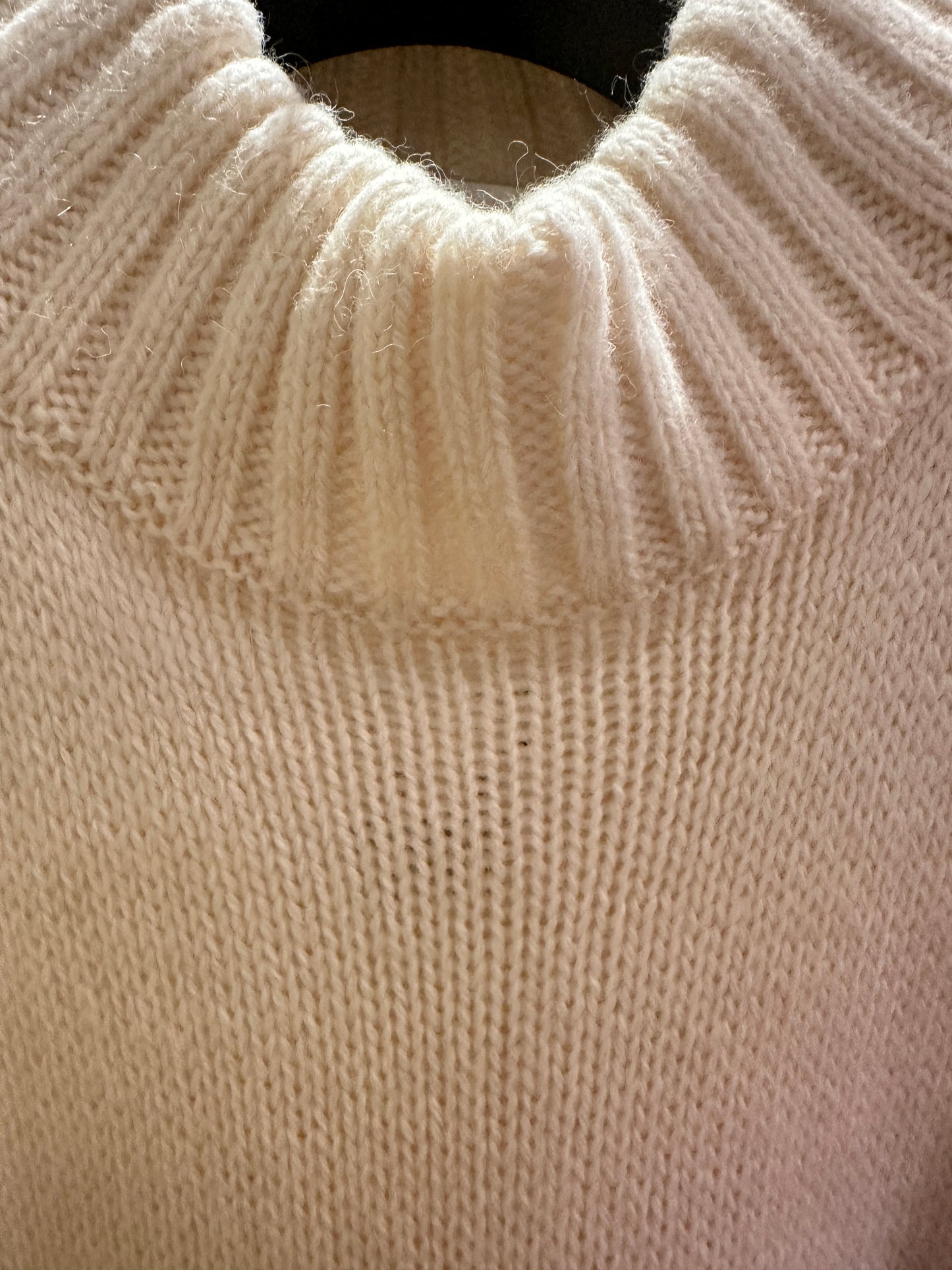 Close-up of the creamy white Laurel Sweater, featuring a ribbed neckline and soft texture, perfect for winter style.