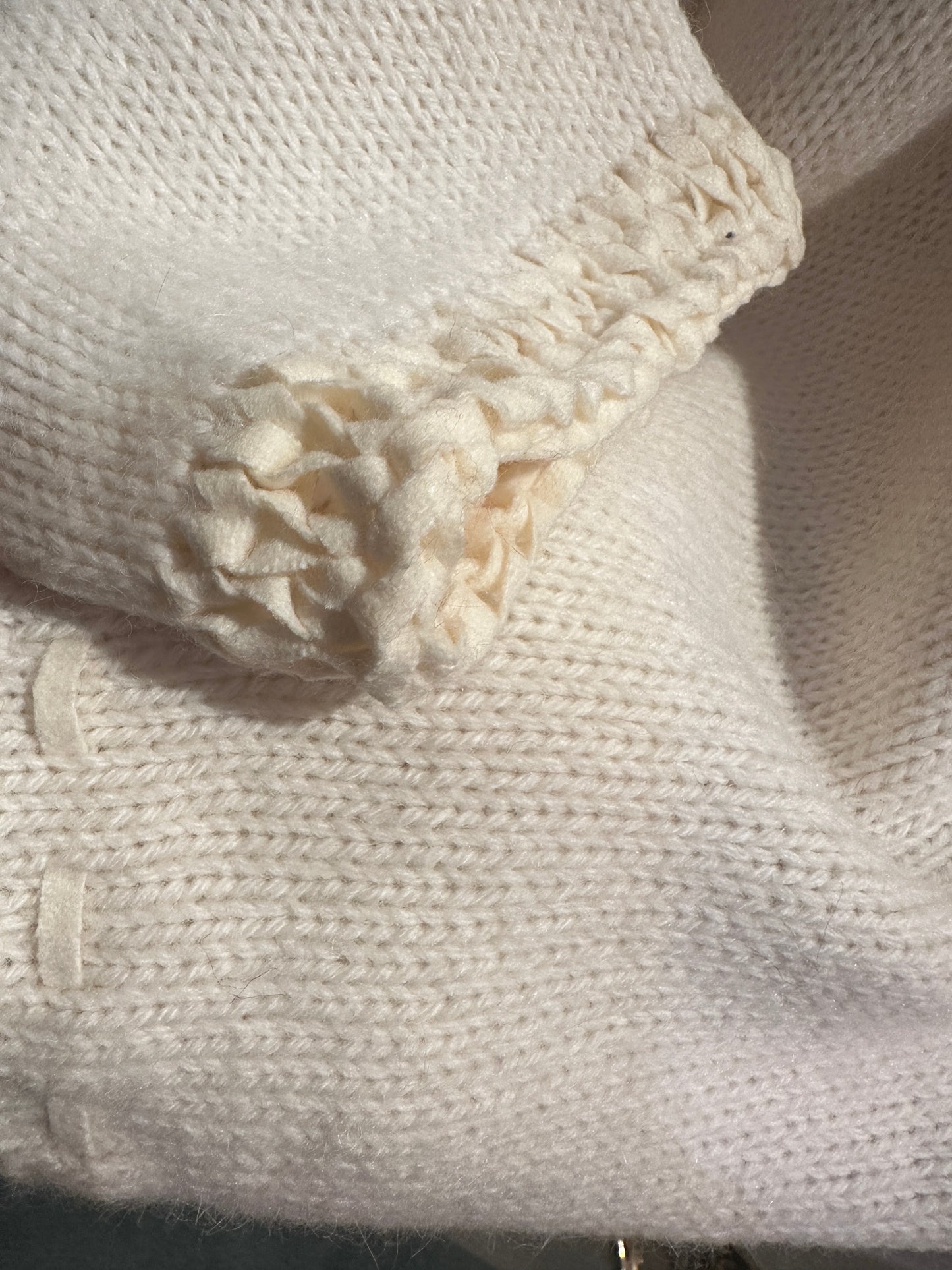Close-up of the creamy white Laurel Sweater showcasing its soft knit texture and unique sleeve design.