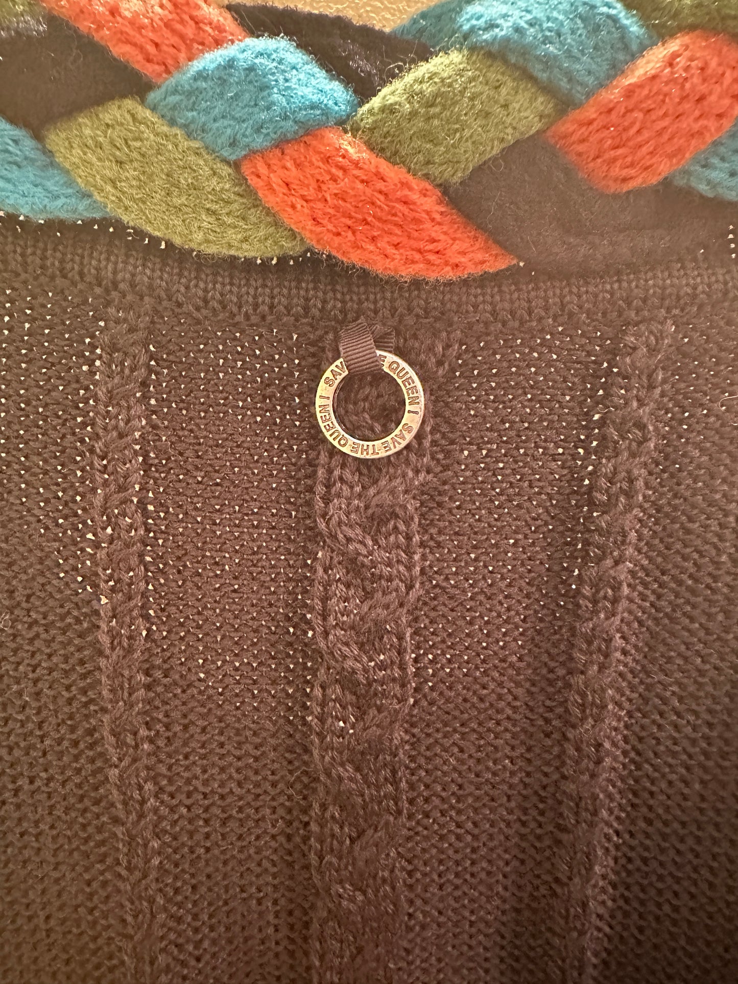 Close-up of Save the Queen Cardigan featuring braid line detail and unique tag, highlighting stylish knitwear craftsmanship.
