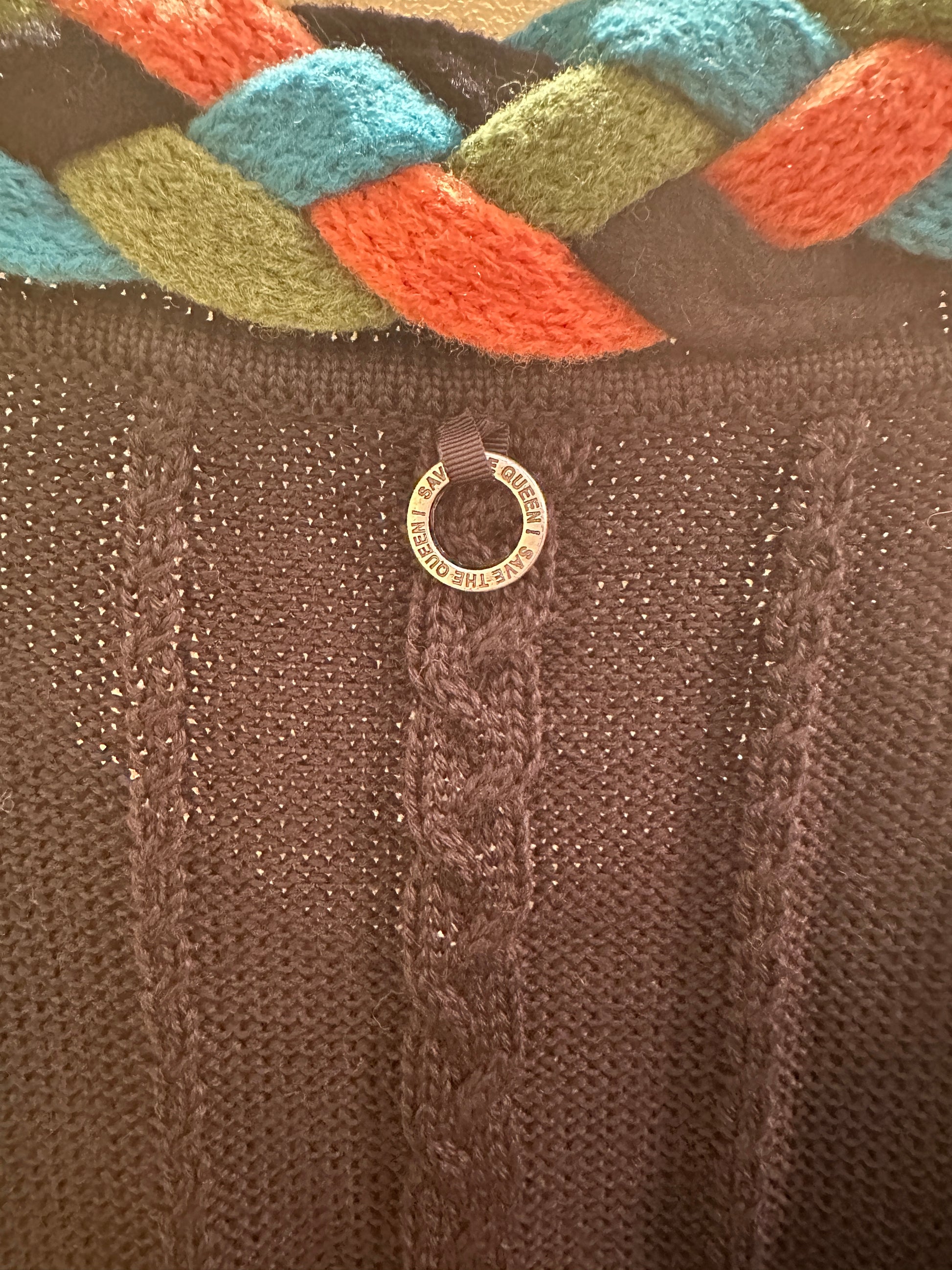 Close-up of Save the Queen Cardigan featuring braid line detail and unique tag, highlighting stylish knitwear craftsmanship.