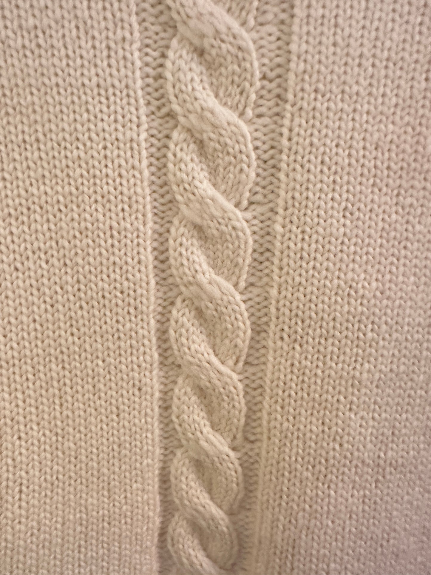 Close-up of a Versace white sweater showcasing the intricate green thread braid along the sleeves.