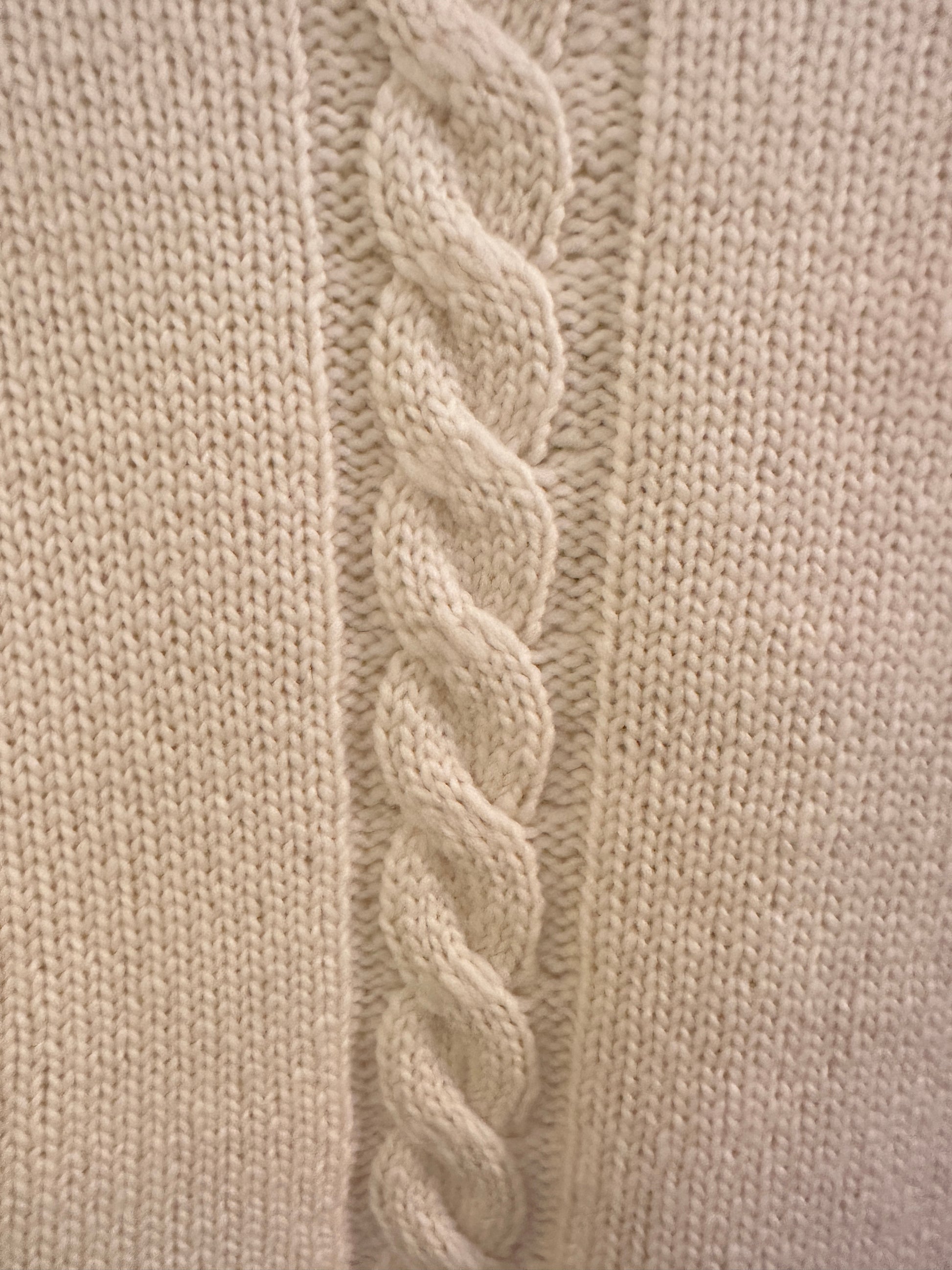 Close-up of a Versace white sweater showcasing the intricate green thread braid along the sleeves.