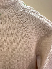 Versace white sweater detail showing sophisticated knit texture and green thread braid design.