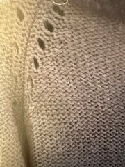 Close-up of the knit texture and detail of the Essentiel Cardigan Sweater in dark fabric with subtle patterns.