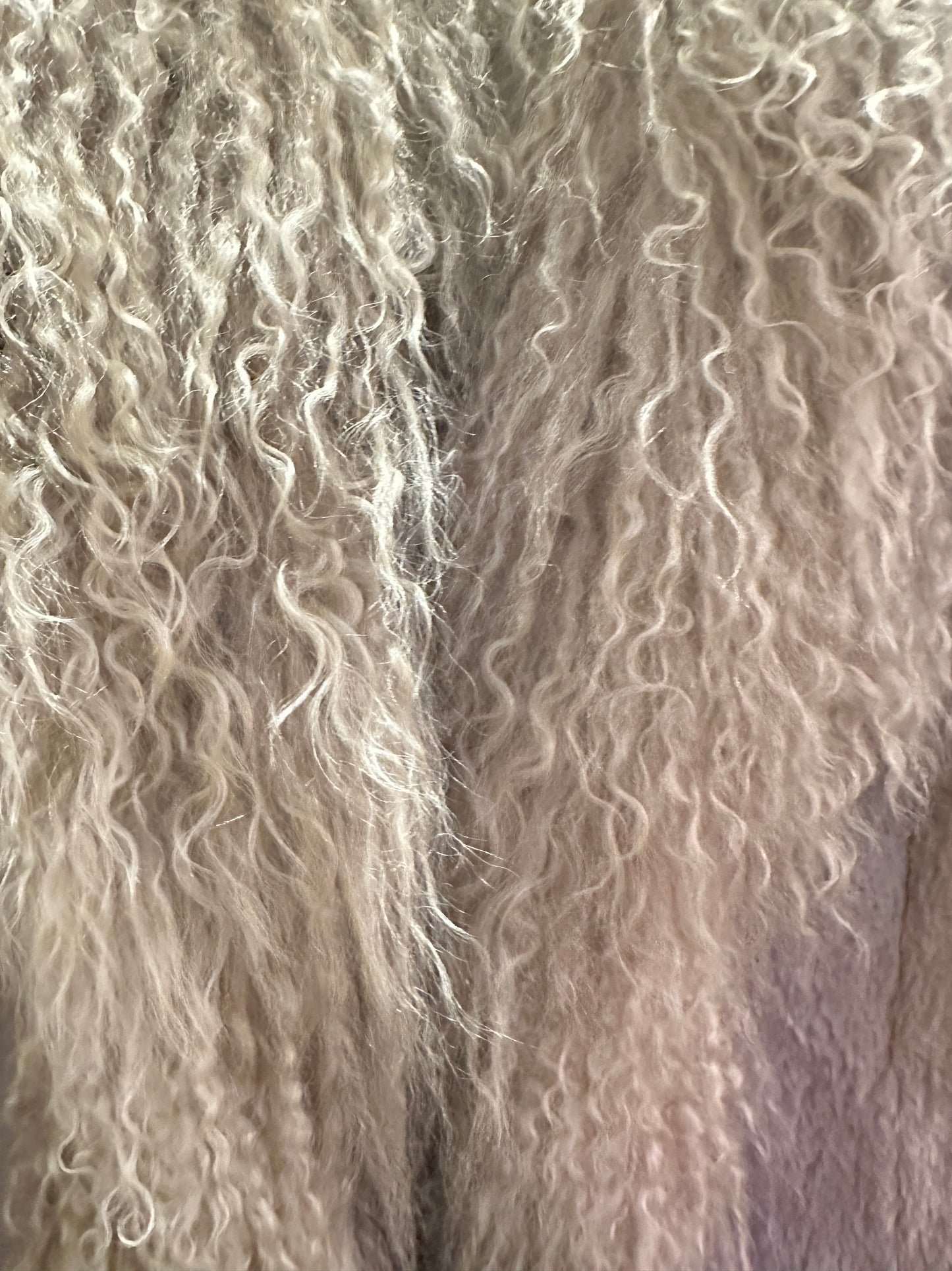 Close-up of soft rabbit fur texture in light gray, showcasing the luxurious curls of the Essential Long Fur Coat.
