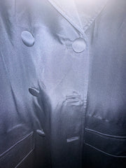 Close-up of Versace black coat fabric with double-breasted buttons and sleek design.