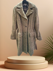 Marccain long coat in wool blend with vintage cut and detachable belt, styled on a minimal display.
