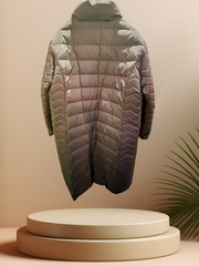 Apropos Long Down Coat displayed on a pedestal, showcasing its sleek design and lightweight insulation for winter warmth.