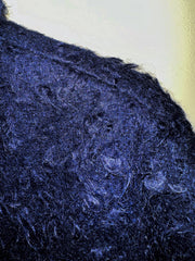 Close-up of textured dark blue fabric, showcasing the unique fibers and style perfect for winter clothing.