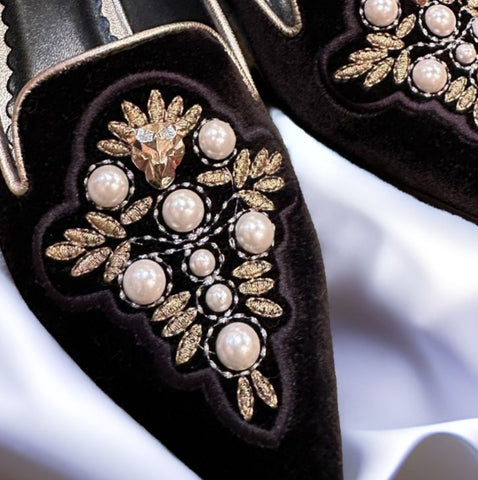 Close-up of Marccain black slip-on flats featuring elegant pearl and gold thread embellishments.