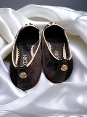 Marccain black slip-on flat shoes with golden thread and pearl decoration on a satin fabric background.