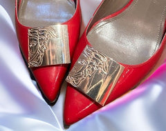 Versace red kitten heels with gold accents, showcasing style and elegance on satin background.