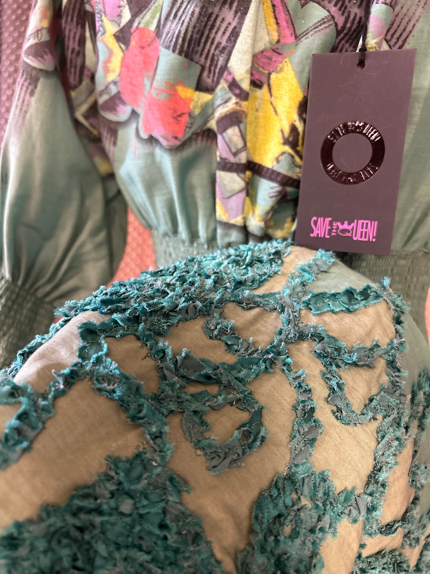 Close-up of Save The Queen green dress showcasing intricate textures and vibrant floral patterns.