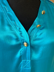 Close-up of Versace silk shirt in vibrant turquoise, featuring elegant buttons and luxurious fabric texture.