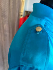 Close-up of a Versace silk shirt in vibrant blue featuring a gold-buttoned shoulder detail.