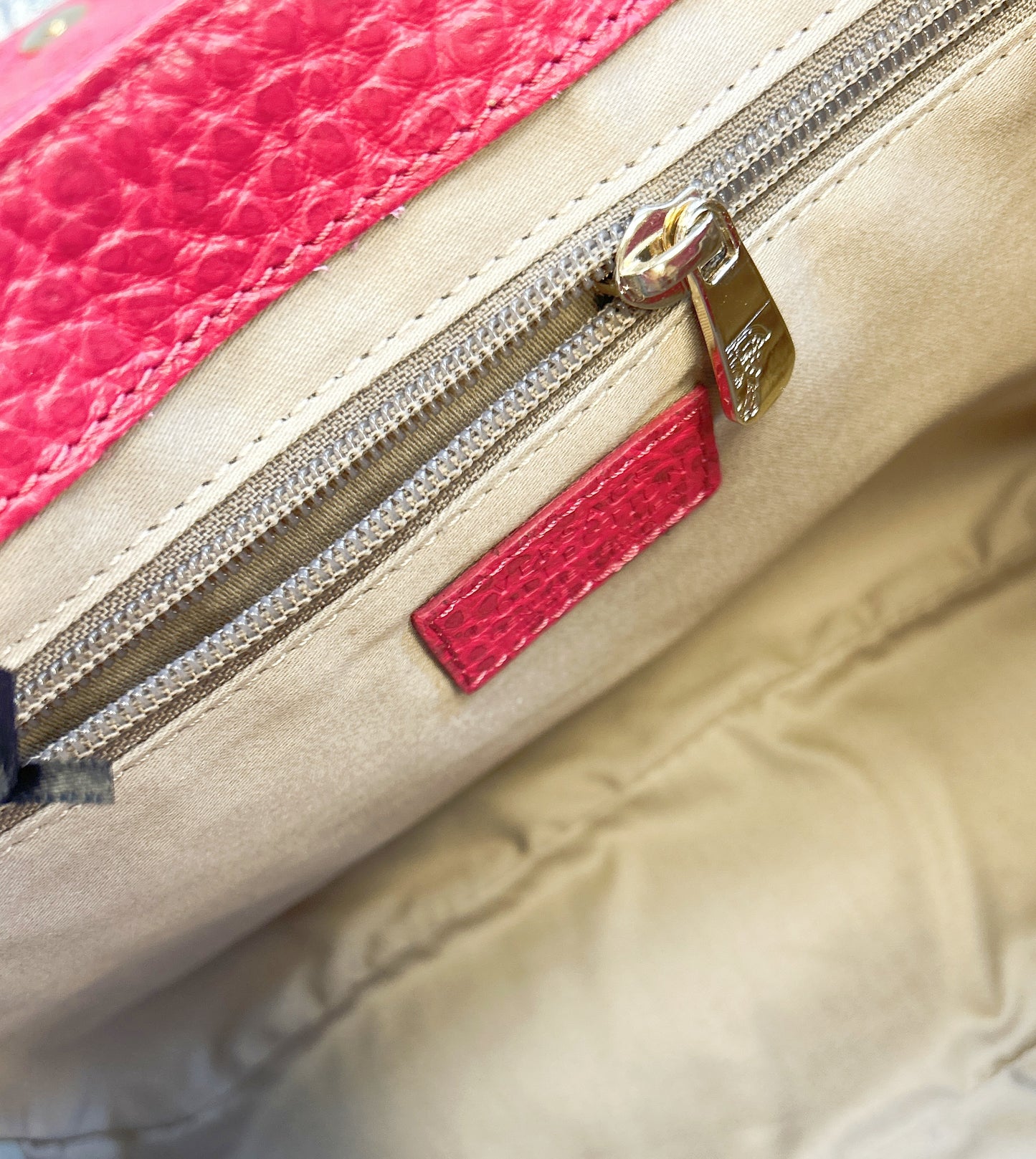 Interior close-up of a Versace Leather Bag showcasing the zippered compartment and vibrant pink accents.