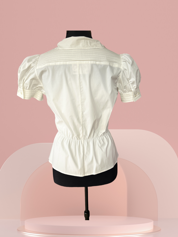 Pennyblack White Blouse with puff sleeves and waistline cut displayed on a mannequin against a soft pink backdrop.
