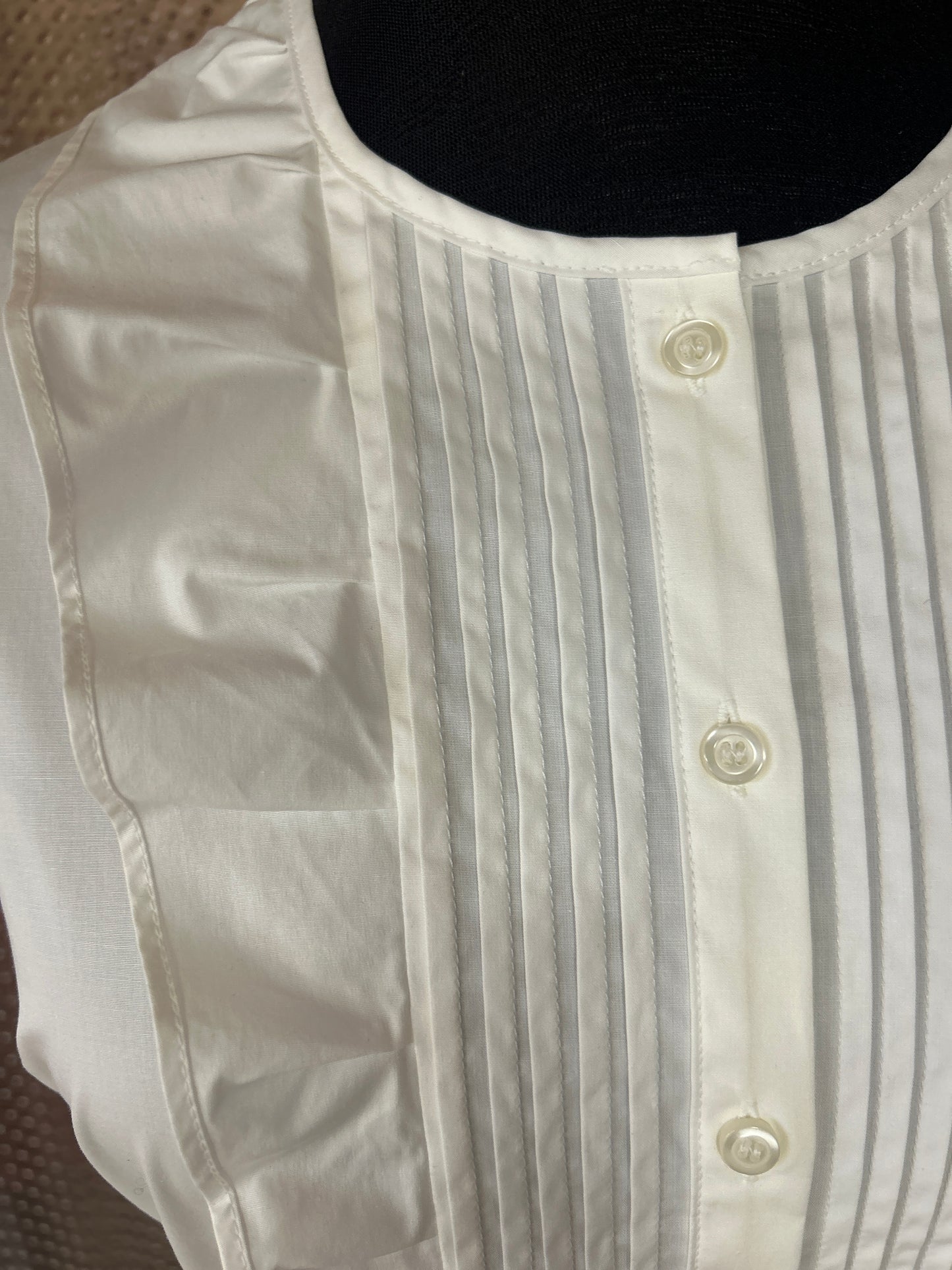 Close-up of a Pennyblack white blouse featuring puff sleeves and button placket with pleated design.