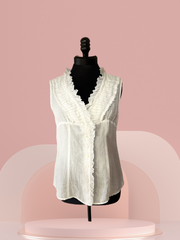 White linen Seventy Cotton Vest with ruffled collar displayed on a mannequin against a pink background