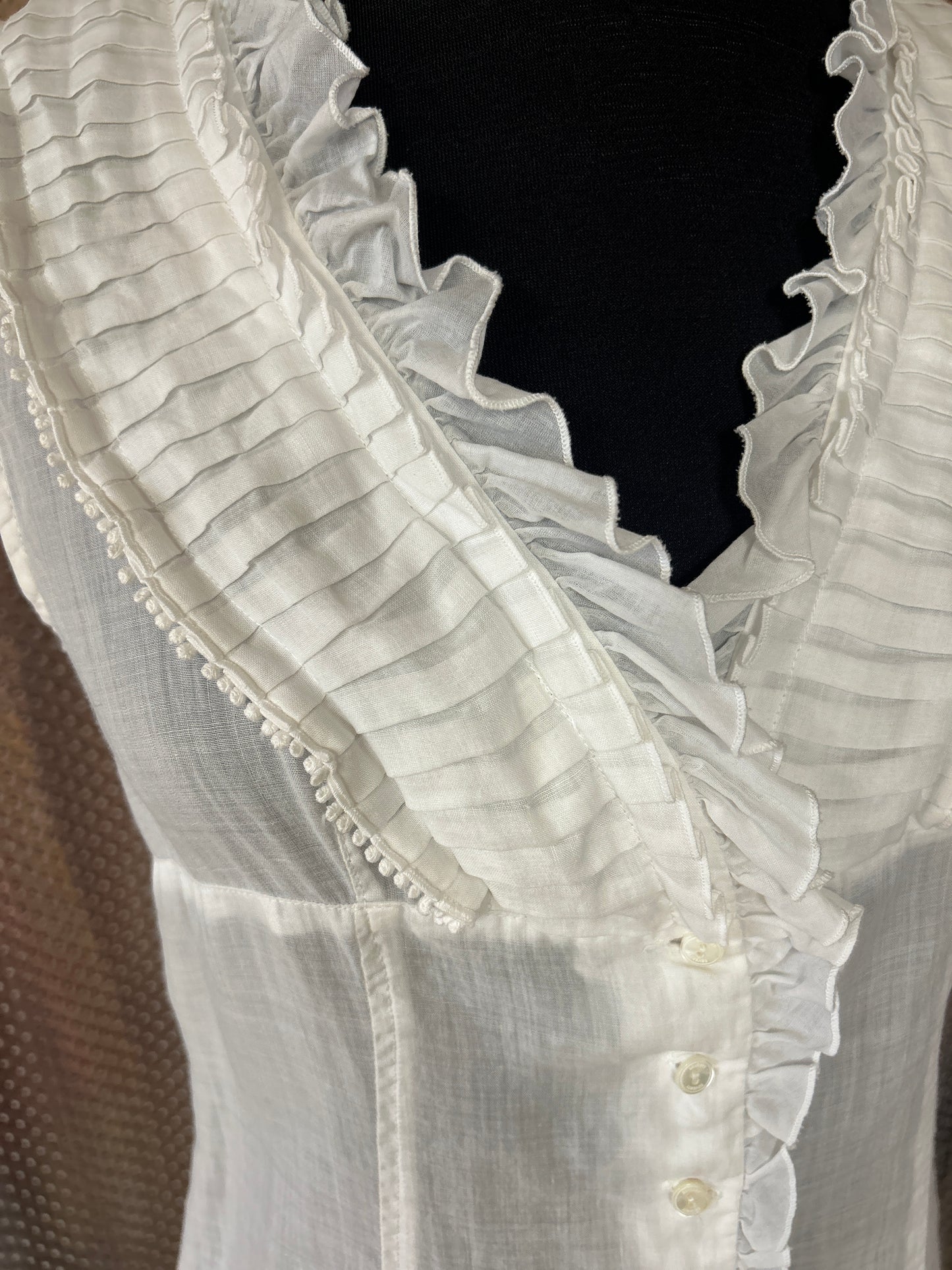 Close-up of Seventy Cotton Vest in white linen, featuring ruffled collar and button details, perfect for summer outfits.