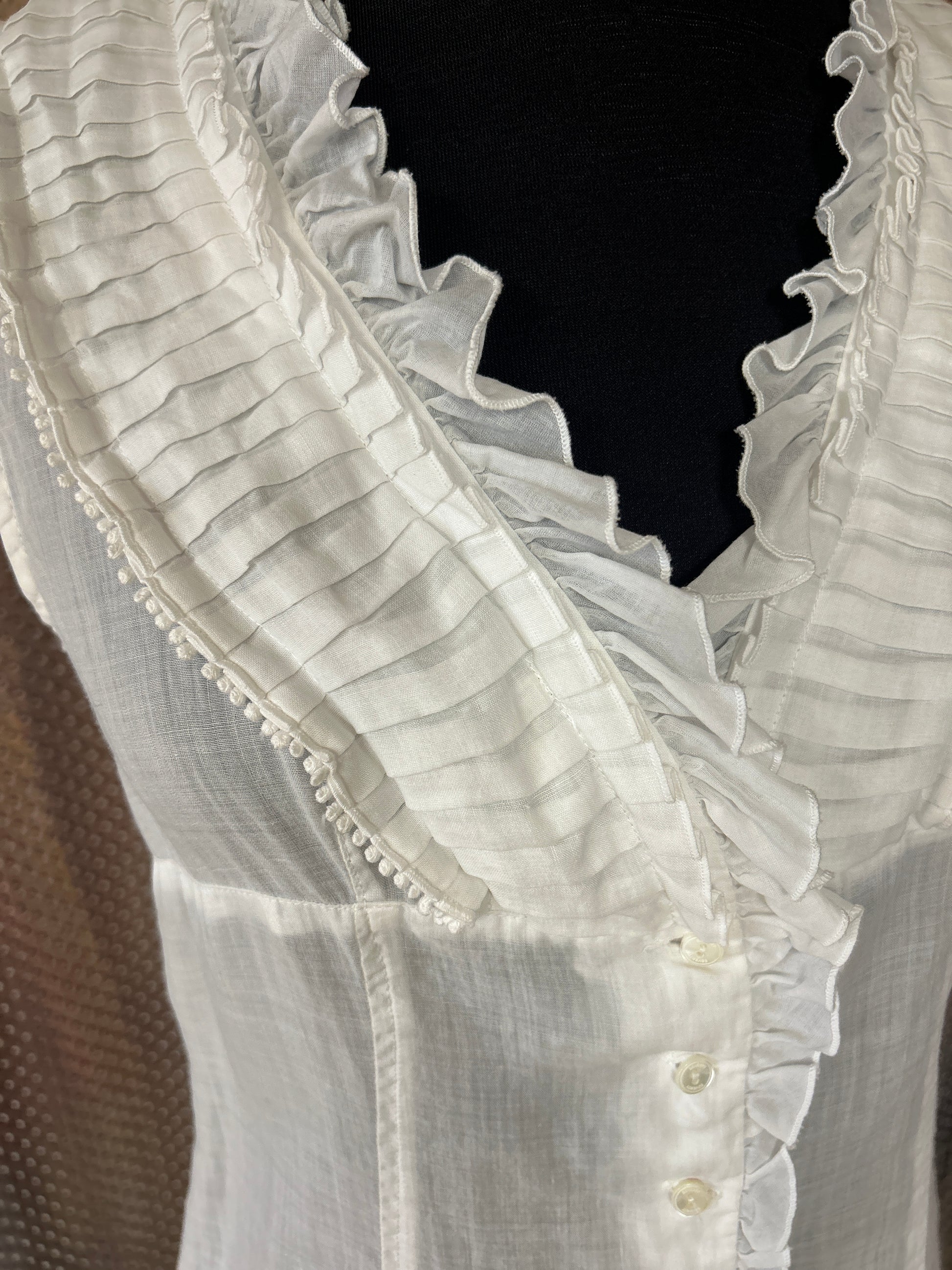 Close-up of Seventy Cotton Vest in white linen, featuring ruffled collar and button details, perfect for summer outfits.