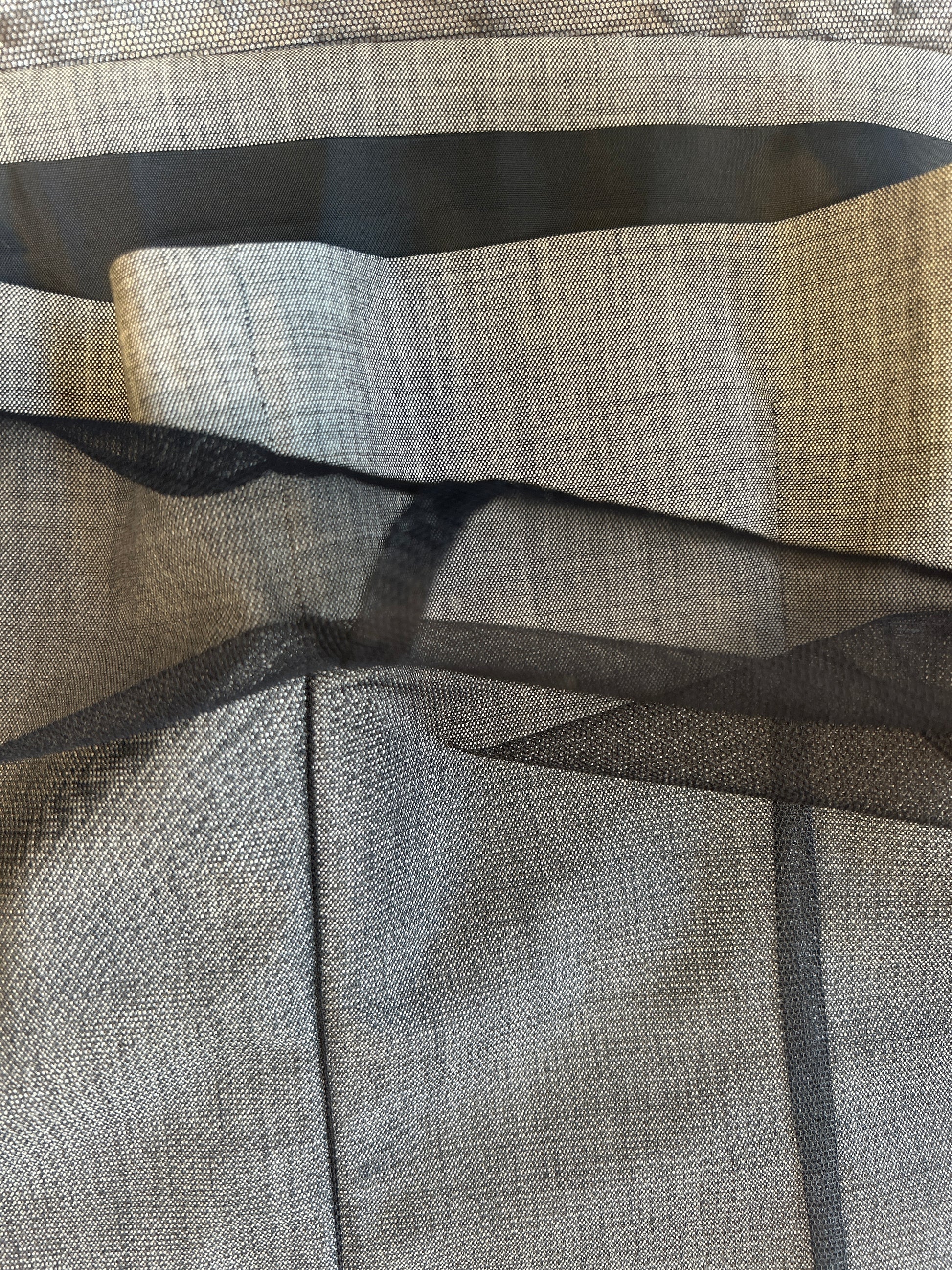 Close-up of textured gray wool fabric layered with black net, showcasing the materials used in the Laurel Vest.
