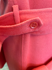Close-up of the button and belt detail on a Marccain coral red long coat made of wool and cashmere.