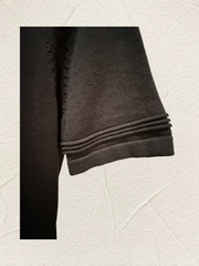 Close-up of a black sweater sleeve showcasing knit texture and detailing, ideal for casual or formal wear.