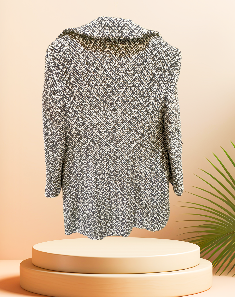 Marccain black and white houndstooth coat displayed on a pedestal with a modern background, showcasing its stylish design.