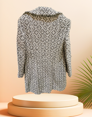 Marccain black and white houndstooth coat displayed on a pedestal with a modern background, showcasing its stylish design.